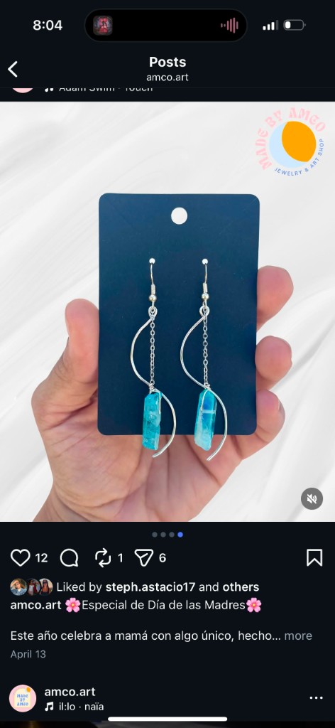 Handmade silver-tone chain earrings with turquoise crystal drops on a black display card.
